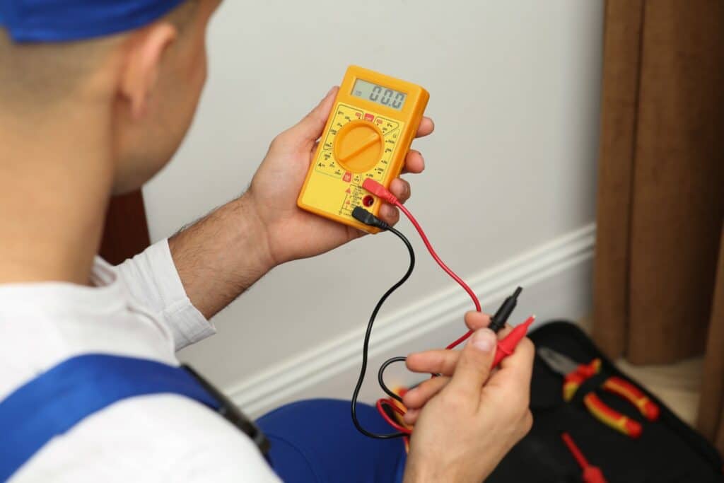 Électricien professionnel 13-Elec effectuant un diagnostic de panne électrique avec testeur de tension à Saint-Cyr-au-Mont-d'Or